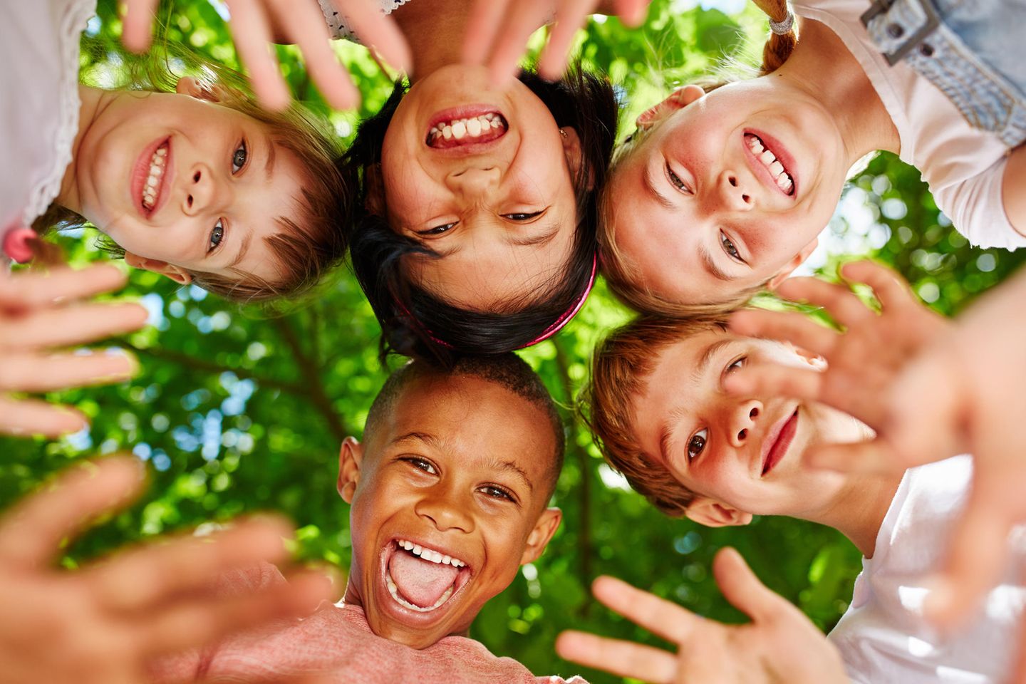 Weltimpfwoche 2023: Fünf Kinder stecken ihre Köpfe zusammen und lachen