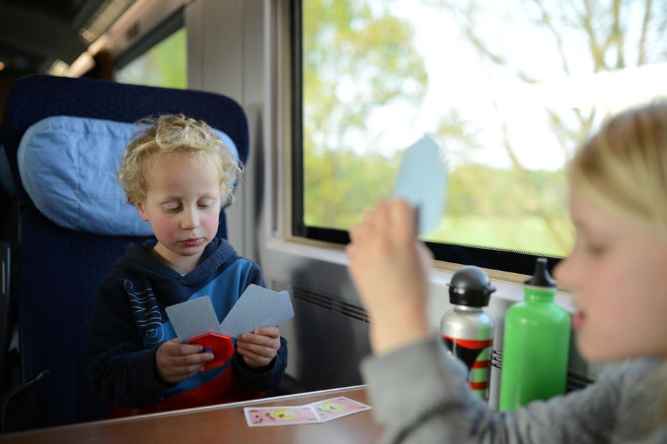 Reisespiele: Zwei Kinder spielen Karten in der Bahn