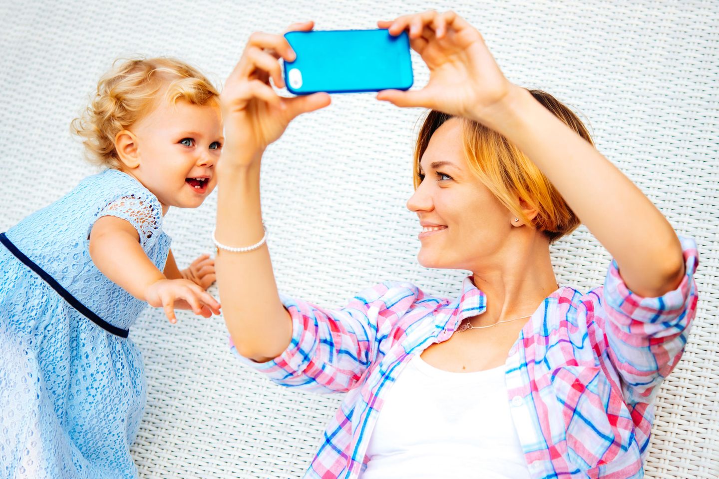 Mutter hält ihr Smartphone auf Kleinkind