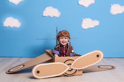 Ein kleiner Junge in einem gebastelten Flugzeug aus Pappkarton