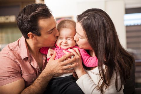 Mama und Papa küssen ihr Baby auf beide Wangen