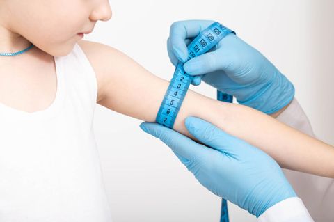 Untergewicht bei Kindern: Messung des Oberarmumfanges bei einem Kleinkind mit einem blauen Maßband