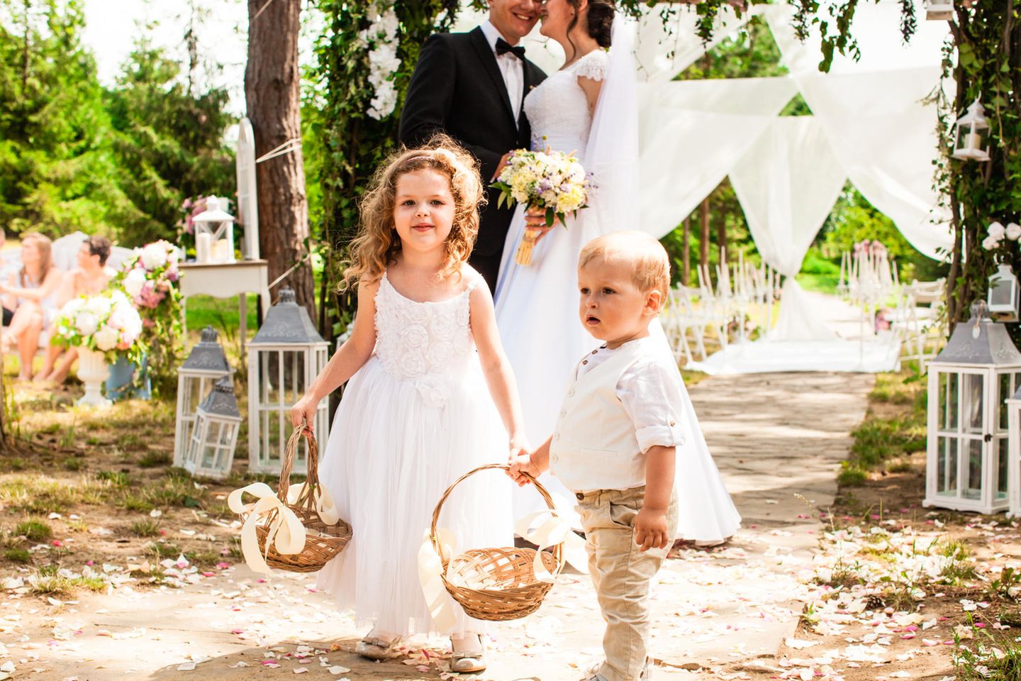 Heiraten mit Kind: Zwei Kinder mit Blumenkörbchen stehen händchenhaltend vor dem Brautpaar.