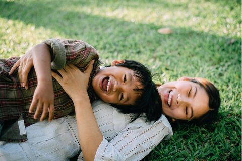Mutter-Sohn-Sprüche: Mama und Junge liegen lachend im Gras
