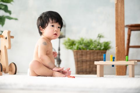 Mongolenfleck: Kleiner Junge mit blauen Muttermalen sitzt auf dem Boden