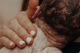 Eigenständige Geburt: Mutter hält Baby nach der Entbindung