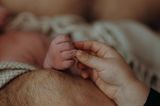 Eigenständige Geburt: Geschwisterkind hält Hand des Babys