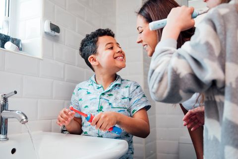 Elektrische Zahnbürsten für Kinder im Vergleich: Junge zeigt Mama seine geputzten Zähne