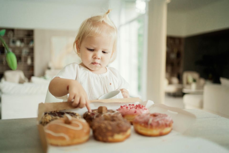 Kinderernährung: Kleinkind zeigt auf einen Donut