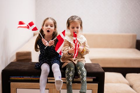Dänische Vornamen: zwei Mädchen sitzen nebeneinander und halten dänische Flaggen