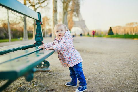Französische Jungennamen: Kleines Kind steht an einer Bank vor dem Eiffelturm