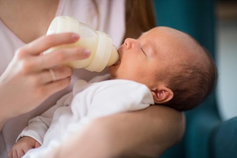 Babyflaschen sterilisieren: Person gibt einem Neugeborenen die Flasche
