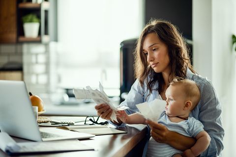 Anne Conelly: Eine junge Mutter sitzt mit einem Baby auf dem Schoß am Arbeitsplatz