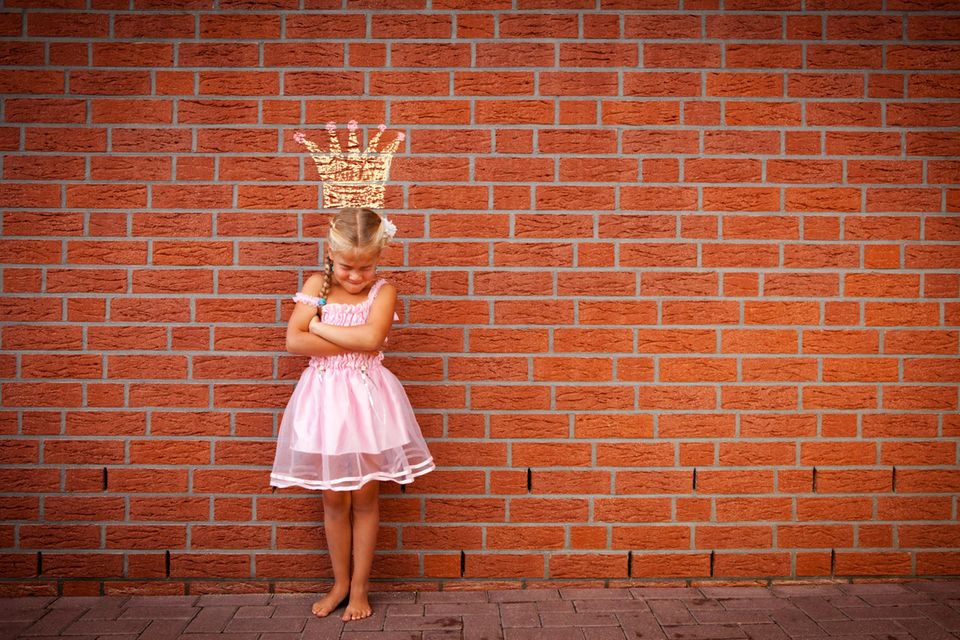 ein Mädchen bockt vor einer Wand mit Prinzessinnen-Krone