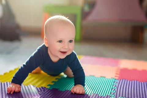 Spielmatte Baby: Baby spielt auf einer bunten Krabbelmatte