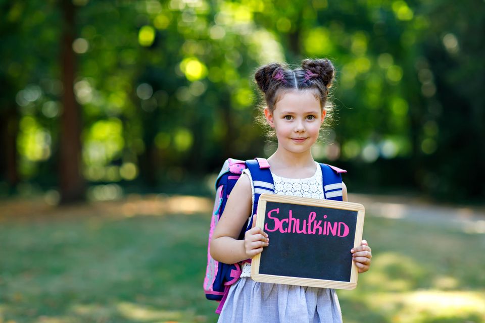 Schule: Mädchen hält eine Tafel mit der Aufschrift "Schulkind" hoch
