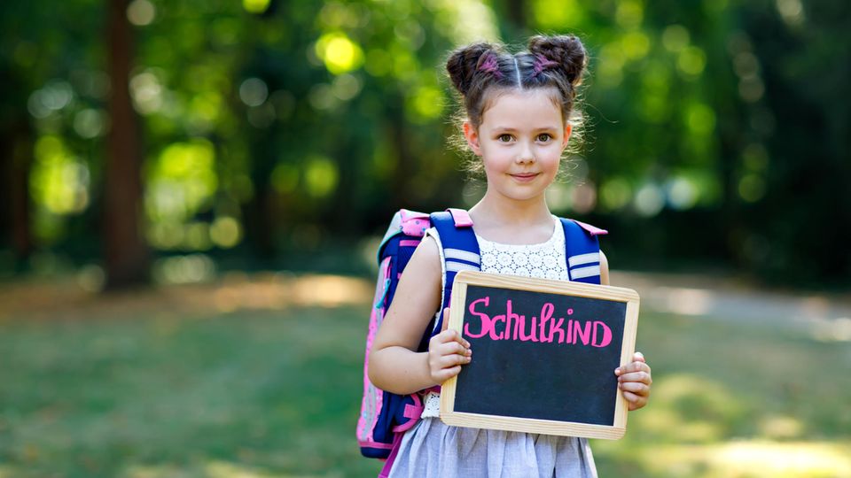 Schule: Mädchen hält eine Tafel mit der Aufschrift "Schulkind" hoch