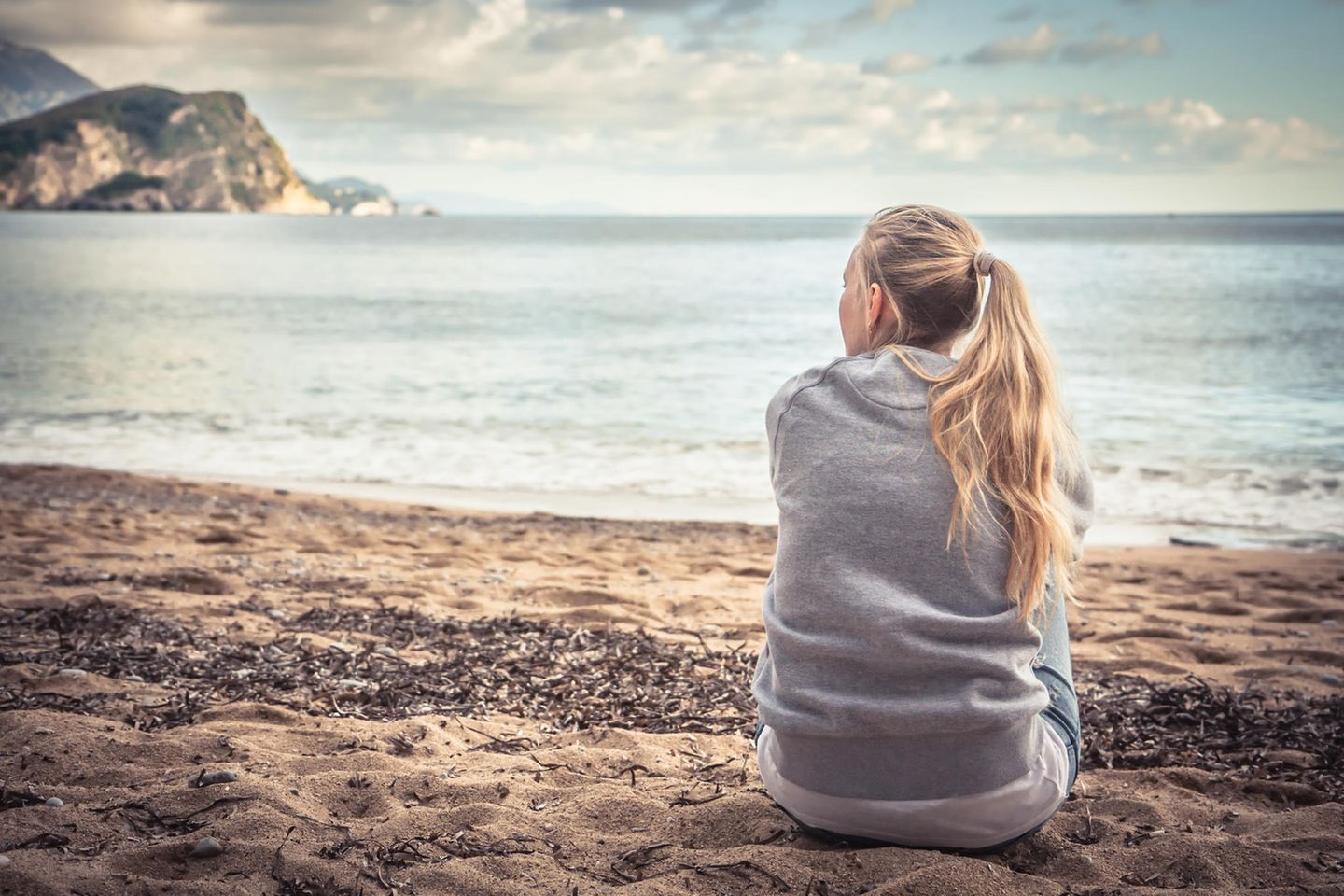 Sandra Teml-Jetter: Eine Frau sitzt am Strand und schaut auf das Meer