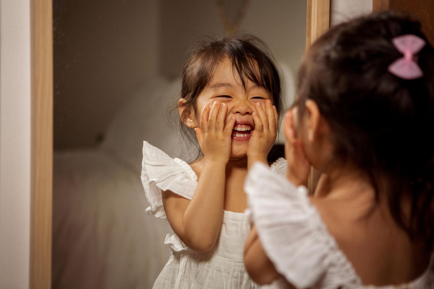Vorbilder: Ein junges Mädchen steht lachend vor dem Spiegel