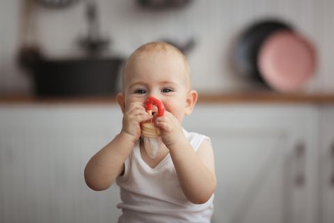 Fruchtsauger für Babys: Ein Baby hält sich einen Fruchtsauger vor das Gesicht