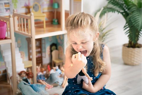 Barbiepuppen im Kinderzimmer: Mädchen schreit vor einem Puppenhaus eine Anziehpuppe an