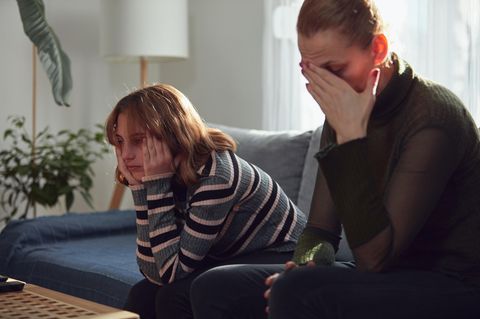Hormonelle Dysbalancen: Eine Mutter sitzt genervt mit ihrem Teenager Kind auf dem Sofa