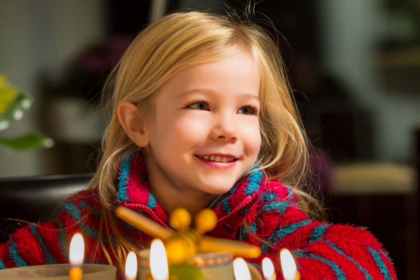Geschenke für 6-Jährige: Glückliches Kind sieht Geburtstagskerzen