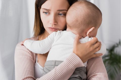 Eine traurige Mutter hält ihr Baby auf dem Arm