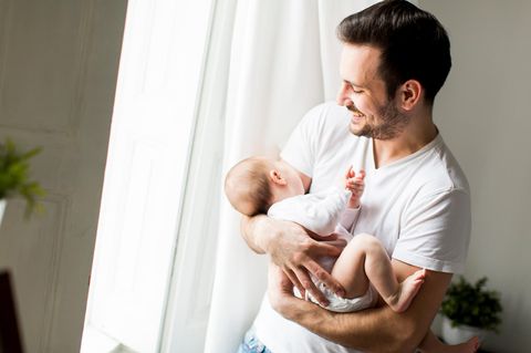 Junger Vater hält Neugeborenes auf dem Arm