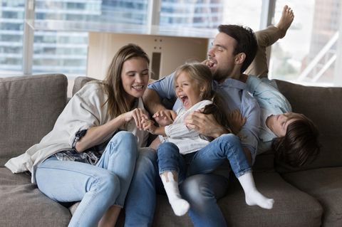 Eltern toben mit zwei Kindern auf dem Sofa