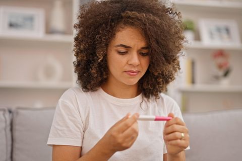 Schwanger trotz negativem Test: Frau schaut skeptisch auf einen Schwangerschaftstest