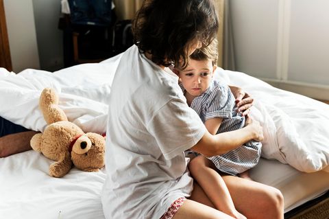 Panikattacken bei Kindern: Mutter tröstet Kind auf dem Bett