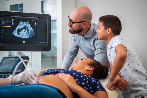 Eine Familie schaut glücklich auf das Ultraschallbild der Mama