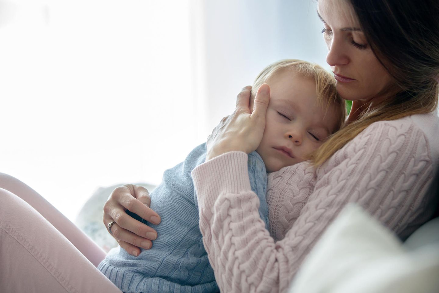 Hirnhautentzündung: Krankes Kind liegt schlafend auf dem Bauch der Mutter
