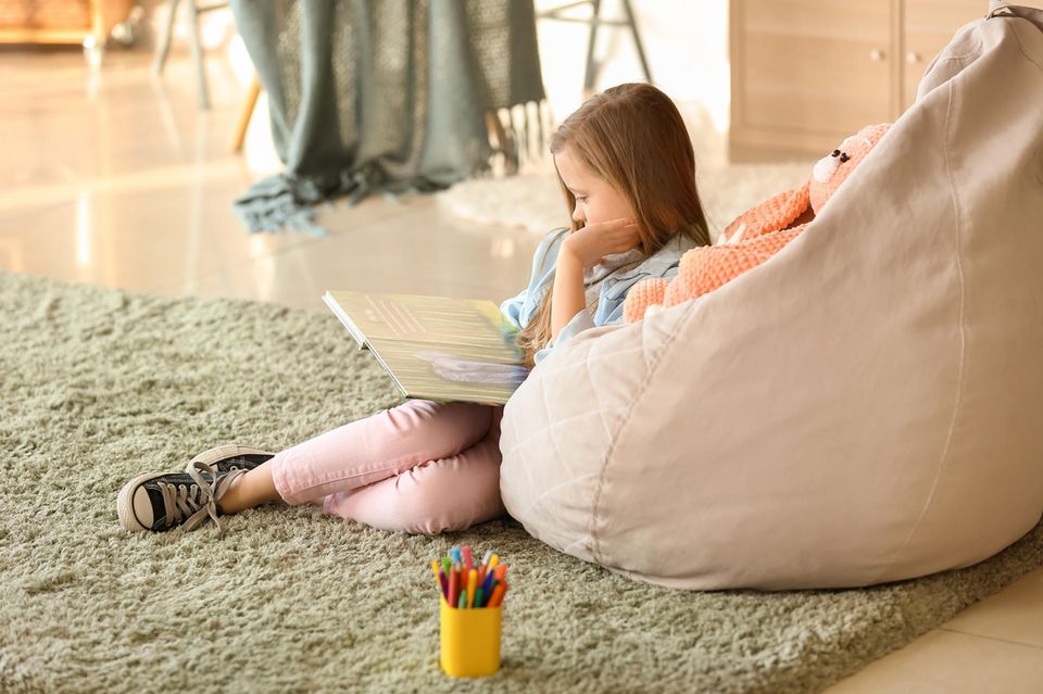 Sitzsack für Kinder: Mädchen lehnt sich zum geütlichen Lesen an einen Sitzsack für Kinder an.