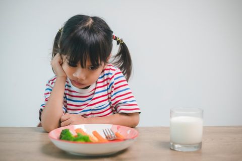 Picky Eater: Mädchen sitzt mürrisch vor ihrem Essen