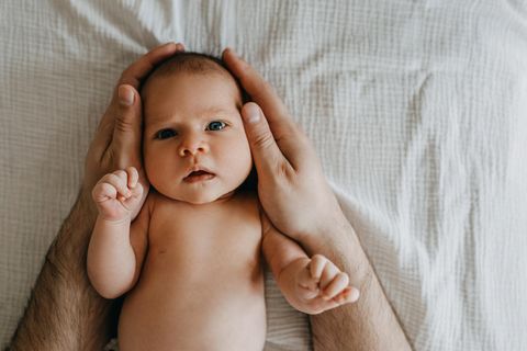 Kephalhämatom: Zwei Hände halten den Kopf eines Neugeborenen