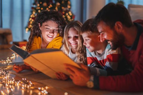 Weihnachtsmärchen: Familie liest Buch am Weihnachtsbaum