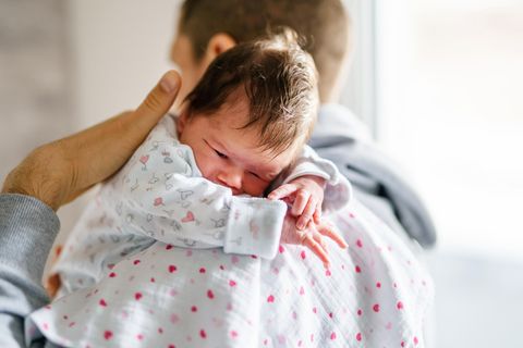 Bäuerchen machen: Neugeborenes liegt über der Schulter einer Person