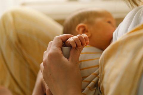Milchtropfen: Baby spielt beim Stillen mit der Brustwarze