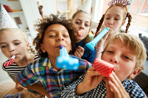 Geschenke für Kinder ab 10 Jahren: Fröhliche 10-Jährige mit Partyaccesoires tröten in die Kamera.