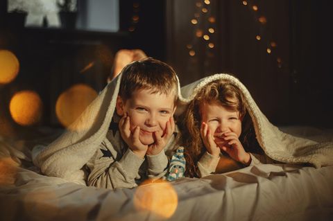 Adventskalender Alternativen: Zwei Kinder liegen morgens gespannt im Bett