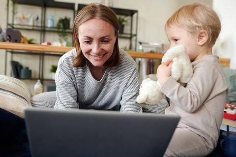 Junge Mutter und ihr Sohn suchen am Laptop nach Black Friday-Angeboten