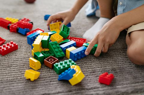 Black Friday Lego-Angebote: Junge spielt mit Lego Bausteinen auf einem Teppich