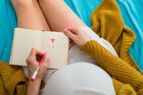 Checkliste für die Schwangerschaft: Schwangere hält ein Notizbuch in den Händen