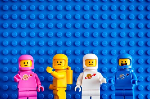 Vier Lego-Figuren stehen vor einer blauen Wand aus Lego-Steinen