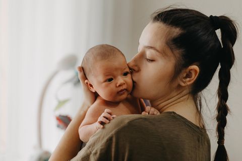 Wochenbett Dauer: Frau mit Neugeborenen auf dem Arm