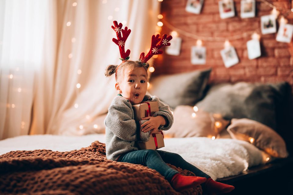 Kleines Mädchen hält aufgeregt ein Weihnachtsgeschenk