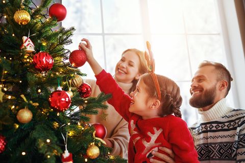 Familie schmückt den Weihnachtsbaum