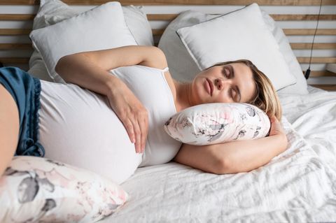 Symphysenlockerung: Schwangere liegt mit Kissen im Bett